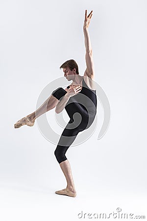 Male Ballet Dancer Man in Black Dance Suit Tights Posing in Ballanced Dance Pose While Stretching His Arm and Leg Muscles in Stock Photo