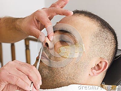 Male barber cutting hairs in the nose by scissors at the adult man in Turkey Stock Photo