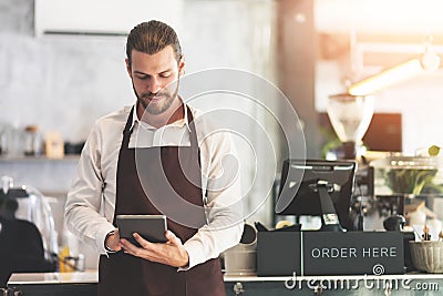 Male barista holding and looking at digital tablet Stock Photo