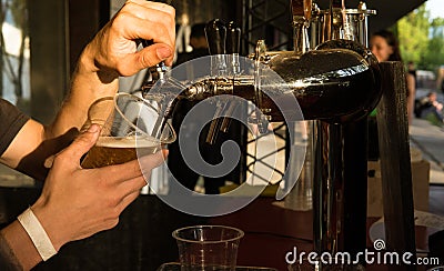 The male bartender pouring beer into a glass close-up. Street food Stock Photo