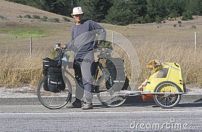 Male bicyclist posing with dog in carrier Editorial Stock Photo