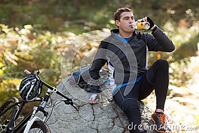 Male biker drinking water in forest Stock Photo