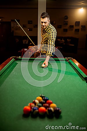 Male billiard player with cue aiming at the table Stock Photo