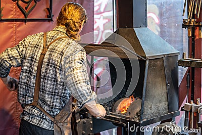 Male blacksmith working in workshop, London. Concept Editorial Stock Photo