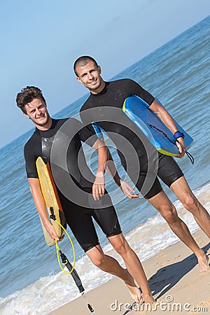 2 male bodyboarders getting out ocean Stock Photo