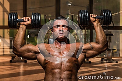 Male bodybuilder doing shoulder press whit dumbbell Stock Photo