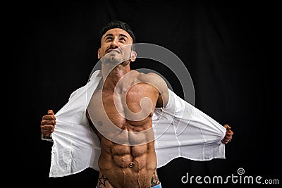 Male bodybuilder taking off his shirt revealing muscular torso Stock Photo