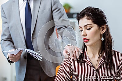 Male boss in grey costume deliberately touching female colleague Stock Photo
