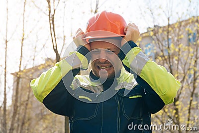 Male builder in helmet closeup, upset in shock, holding his head. Fire fighting concept. house burned down Stock Photo