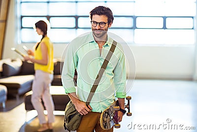 Male business executive standing with skateboard Stock Photo