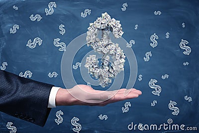 A male businessman`s hand holding a large dollar sign made of banknotes at hand. Stock Photo