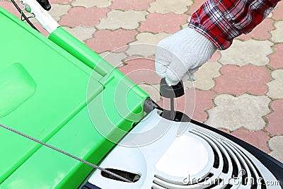 Male Checking the oil level in lawn mower. A green lawnmower. Gardening. Maintenance of equipment Stock Photo