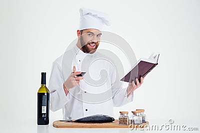 Male chef cook holding recipe book and glass with red wine Stock Photo