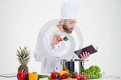 Male chef cook reading recipe book while preparing food Stock Photo