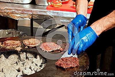 Male chef frying meat burger patties on an open grill Stock Photo