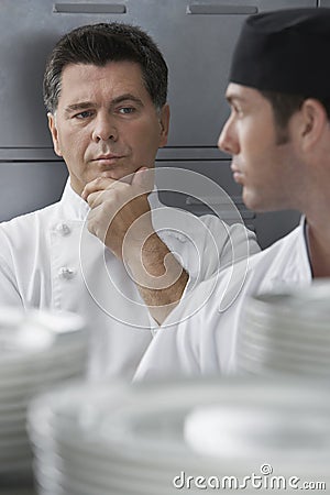 Male Chef Supervising Trainee In Kitchen Stock Photo