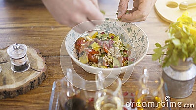 Male chief hands adding parsley to a salad bowl Stock Photo
