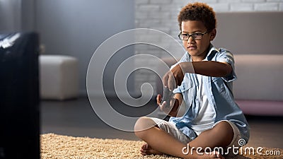 Male child playing on video game console home, sitting floor, gadget addiction Stock Photo