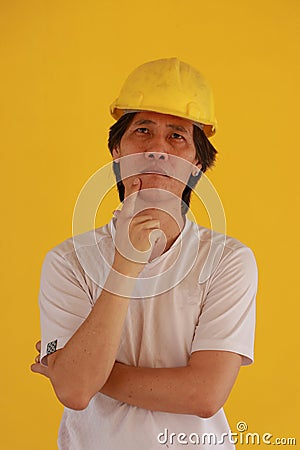 Male civil engineer or architect with yellow helmet and wear white T-shirt on yellow background. and expressing thoughts Stock Photo