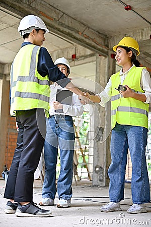 Male civil engineer shaking hands with a female construction inspector in the construction site Stock Photo
