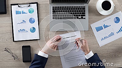 Male in classic suit carefully reading employment agreement at workplace Stock Photo