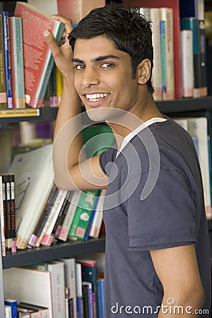 Male college student reaching for a library book Stock Photo