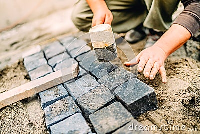 Construction worker using granite cobblestone blocks to create path or sidewalk Stock Photo