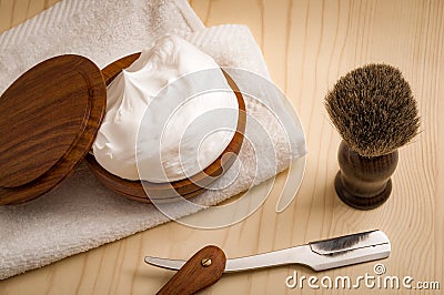 Male cosmetic products and supplies used by men to shave concept with a straight razor, towel, shaving brush and foam on wood Stock Photo