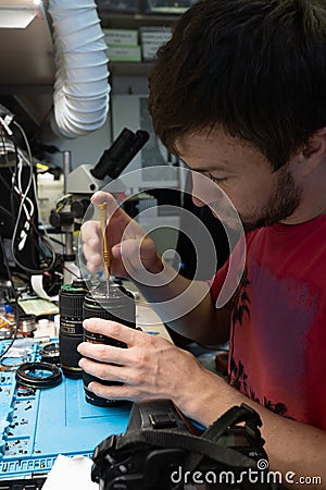 Male craftsman using a miniature screwdriver repairs photographic lenses. Service Center for Repairing Cameras and Photo Editorial Stock Photo