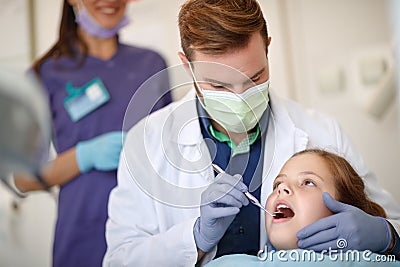 Male dentist looking with dental mirror child`s teeth Stock Photo