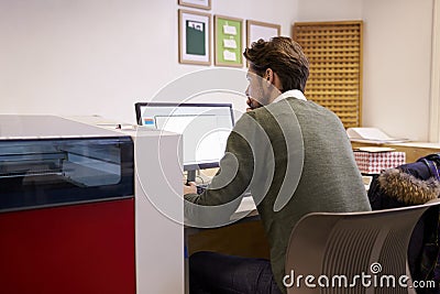 Male Designer Operating CAD System For Laser Cutter Stock Photo