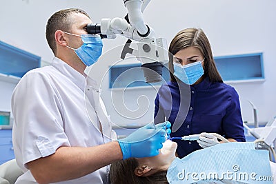 Male doctor dentist treating teeth using dental microscope instruments Stock Photo