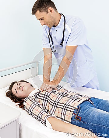 Male doctor doing cardiac massage young woman patient in hospital office Stock Photo