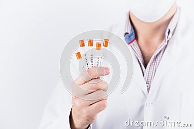 Male doctor endocrinologist in mask holding five insulin syringes on white background Stock Photo