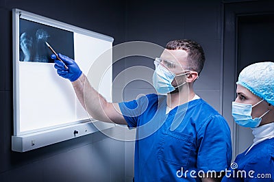 Male doctor and a female nurse stand near a negatoscope and examine an X-ray of a wounded animal. Veterinary medicine concept Stock Photo