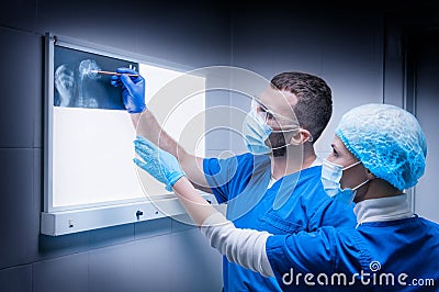 Male doctor and a female nurse stand near a negatoscope and examine an X-ray of a wounded animal. Veterinary medicine concept Stock Photo