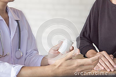 Male doctor giving bottle of medicine to female patient in a hospital Stock Photo