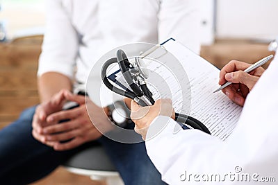 Male doctor hand hold silver pen filling patient history list Stock Photo