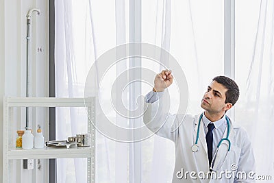 Male doctor hung stethoscope on neck and hold pen to write on air in a conceptual style Stock Photo