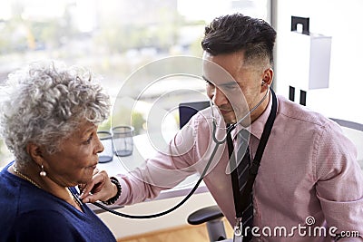 Male Doctor In Office Listening To Senior Female Patients Chest Using Stethoscope Stock Photo