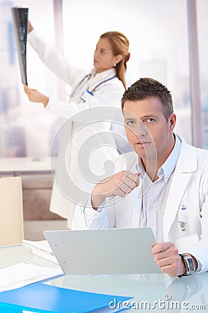 Male doctor sitting at desk doing paperwork Stock Photo