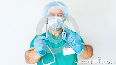 The male doctor smiles and holds a syringe and a vaccine in his hands. Friendly cheerful doctor in disposable cap and mask Stock Photo