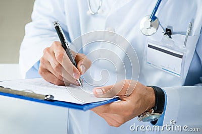 Male Doctor Writing On Medical Document Stock Photo