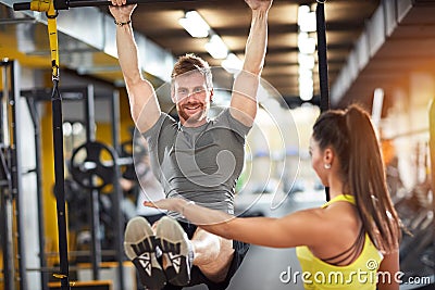 Male doing pull-up exercise with coach assisting Stock Photo