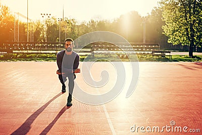 Male doing stretching exercise, preparing for morning workout in the park Stock Photo