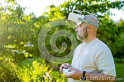 Male drone pilot operating tiny whoop FPV drone in the back yard. FPV experience with FPV glasses during sunset time Stock Photo