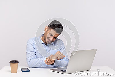 Male employee sitting office workplace with laptop, massaging sore wrist, suffering pinched nerve, stiff muscles Stock Photo