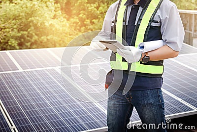 A male engineer holds a tablet to inspect the solar cell system. Stock Photo