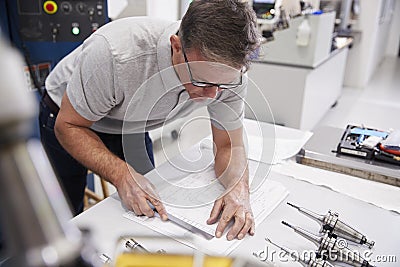 Male Engineer Measuring CAD Drawings In Factory Stock Photo