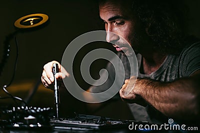 Male engineer upgrading or repairing the laptop computer. Dark photo Stock Photo